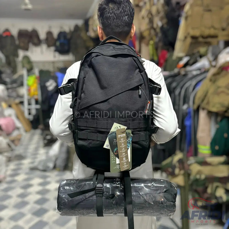 Black tactical backpack with external straps and a bottom-mounted rolled item.
