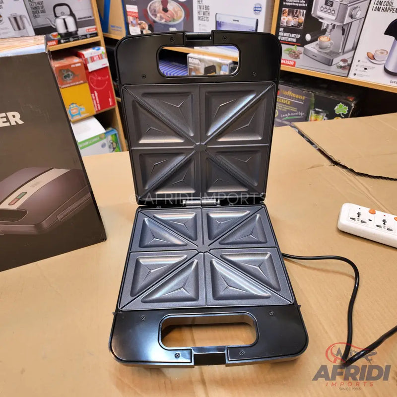 An open, black sandwich maker with four triangular compartments.