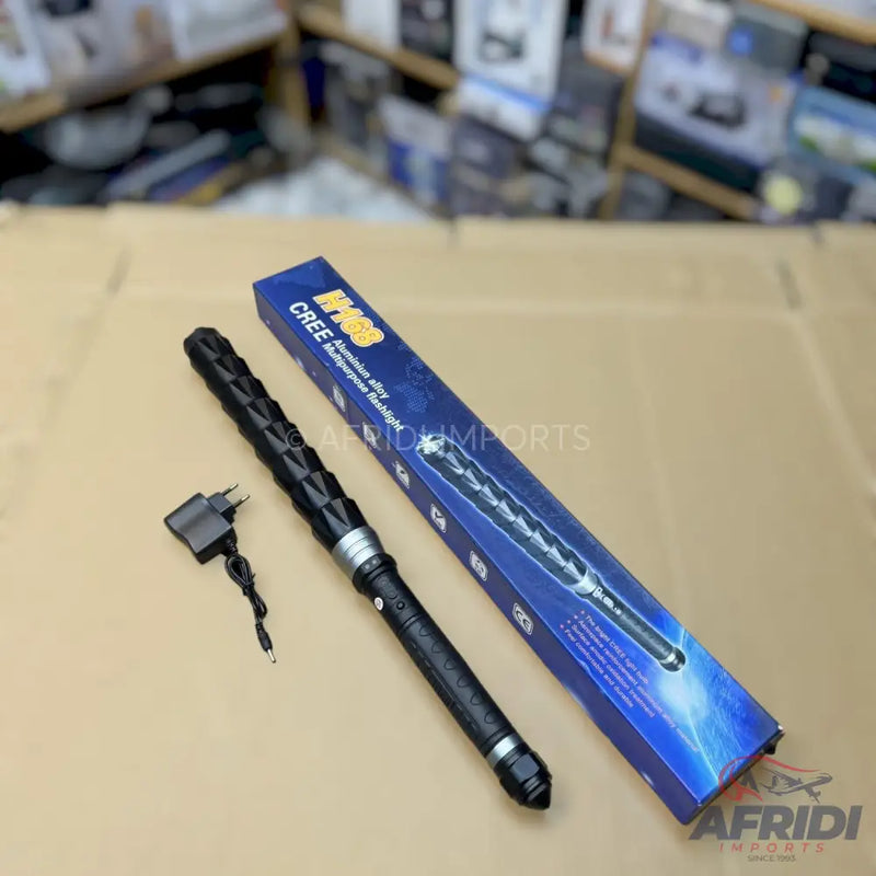 Black metal baton-style flashlight with charger in its packaging.