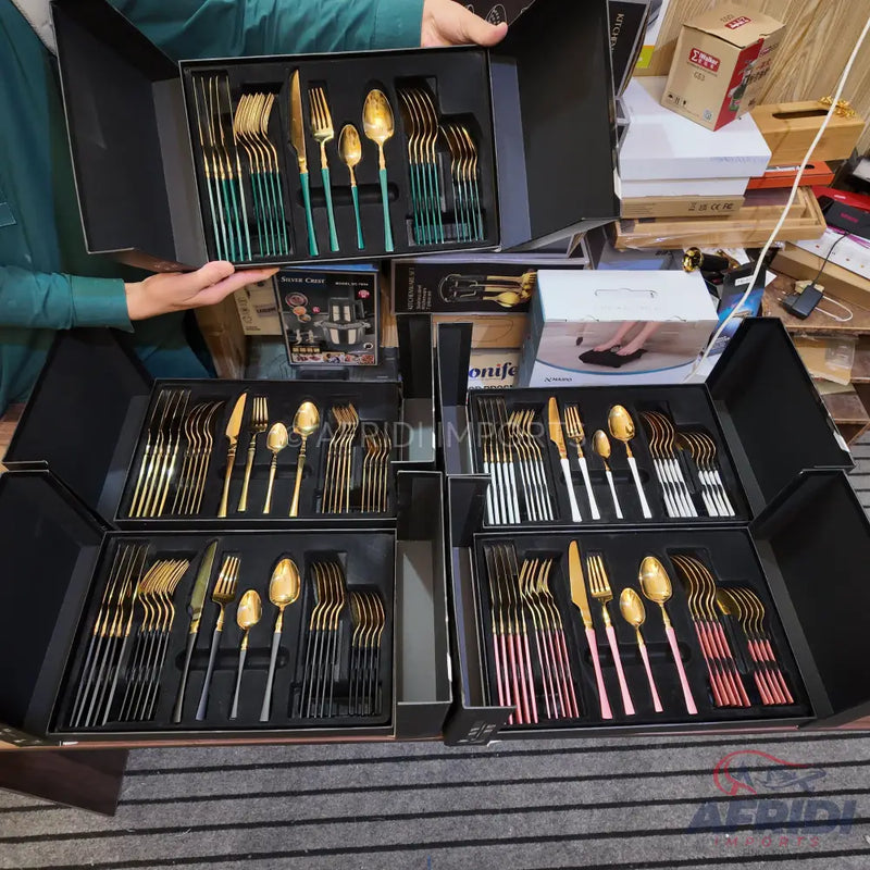 Sets of golden flatware with colorful handles displayed in black presentation boxes.