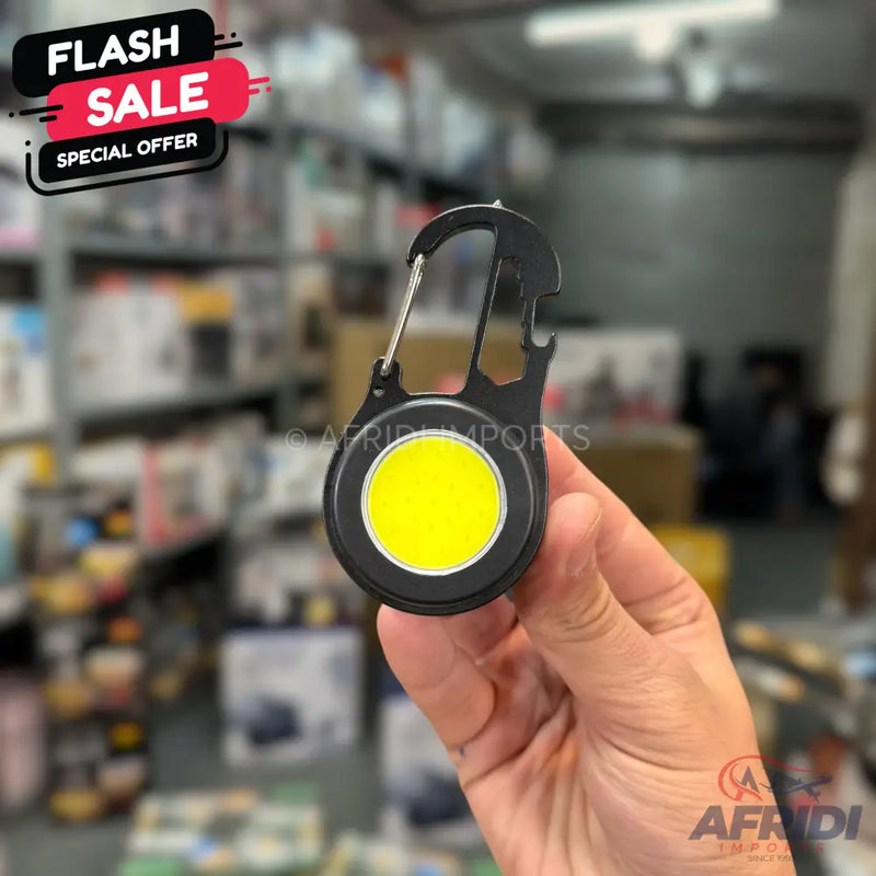 Black carabiner-style keychain with an integrated yellow LED light and a bottle opener.