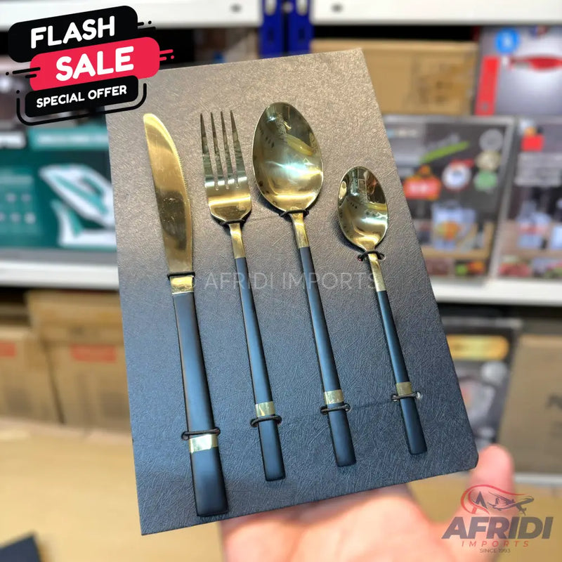 A set of four black and gold utensils including a knife, fork, and two spoons, presented in a black display case.