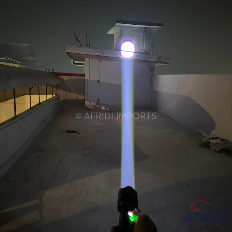 A person holding a flashlight that emits a strong, focused blue-white beam.