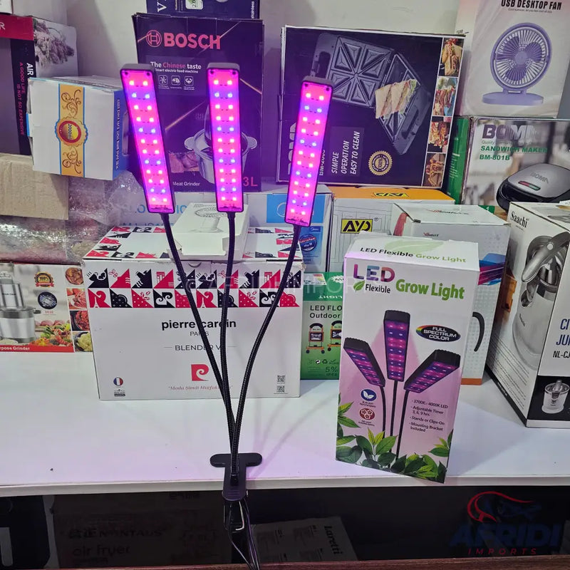 A three-headed LED grow light with flexible arms and a clip-on base, emitting purple light.