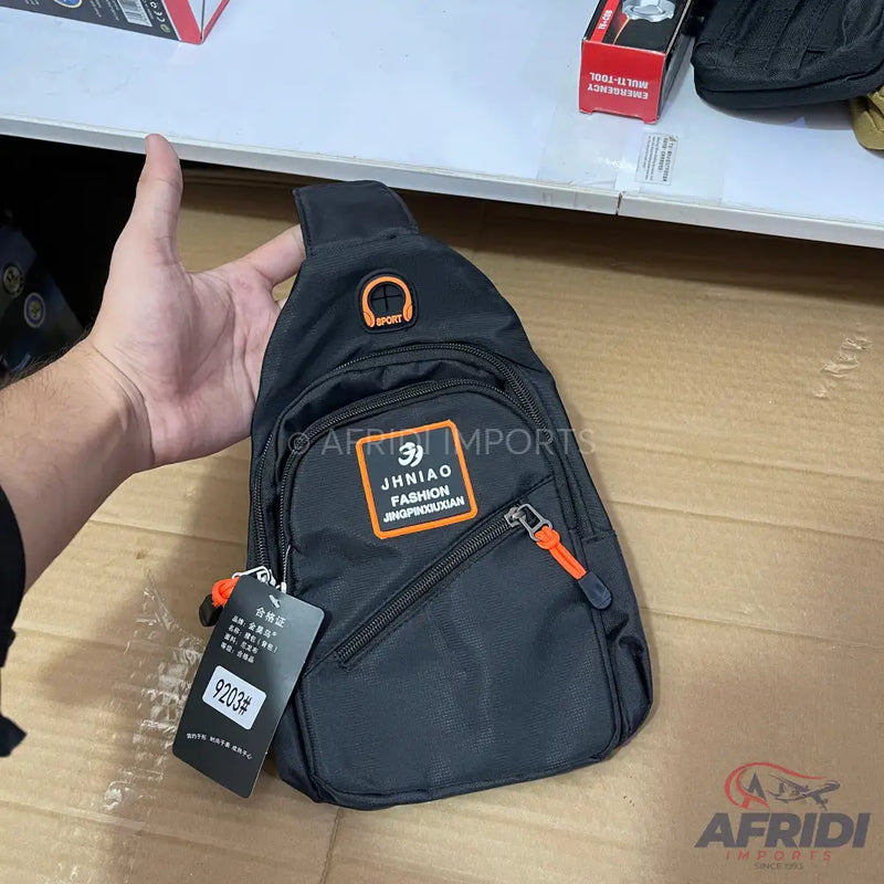 A black sling bag with orange accents and multiple zippered compartments.