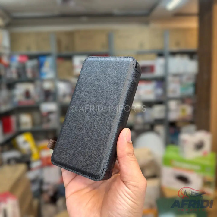 A person holding a black, textured phone case with a flip cover.
