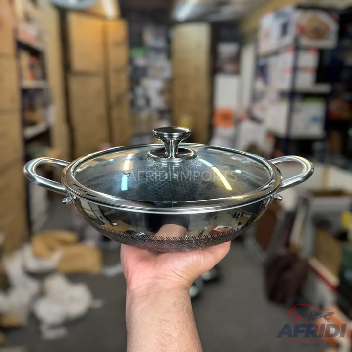 Shiny silver-colored metal pot with two handles and a clear glass lid.