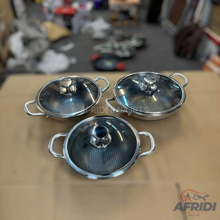 Three stainless steel cooking pots with glass lids and honeycomb patterns.