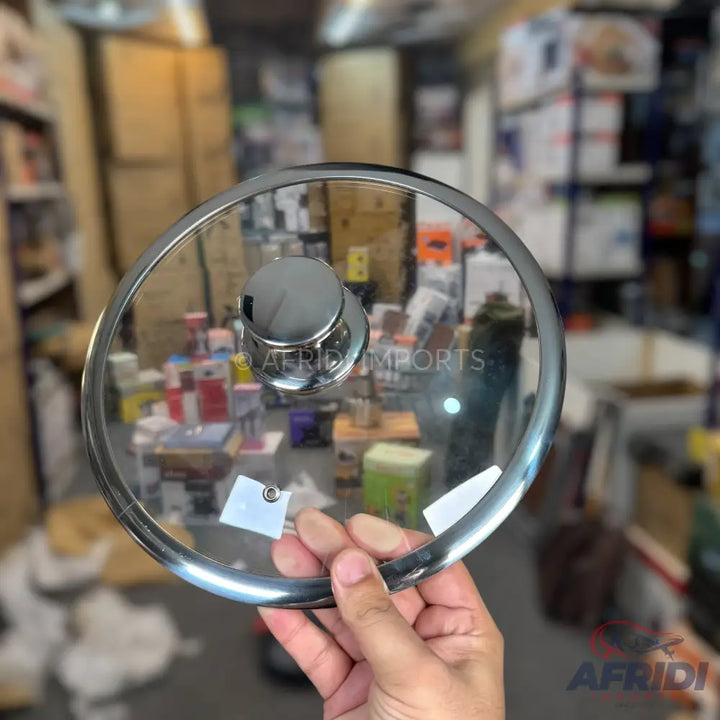 A round, transparent glass lid with a metallic rim and a silver knob handle.