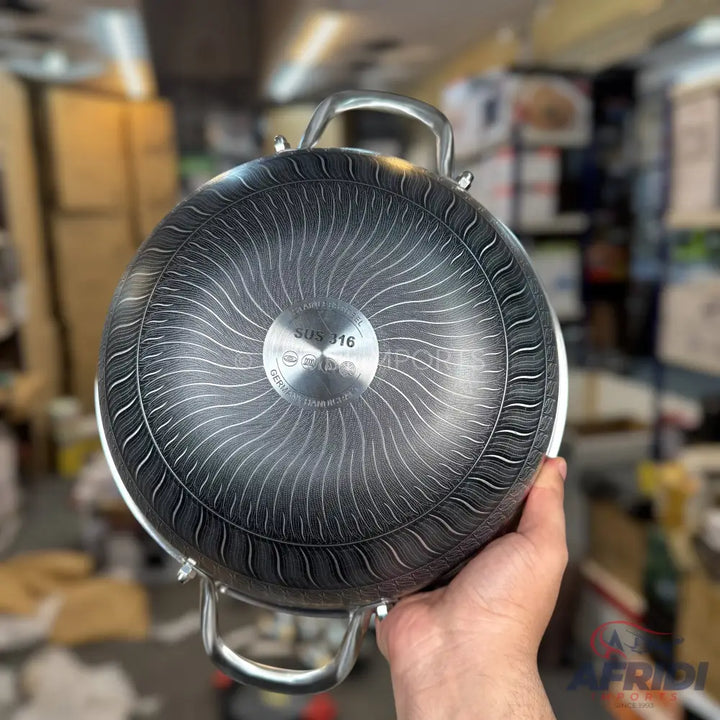 The underside of a dark-colored stainless steel cooking pot with a wavy patterned base.