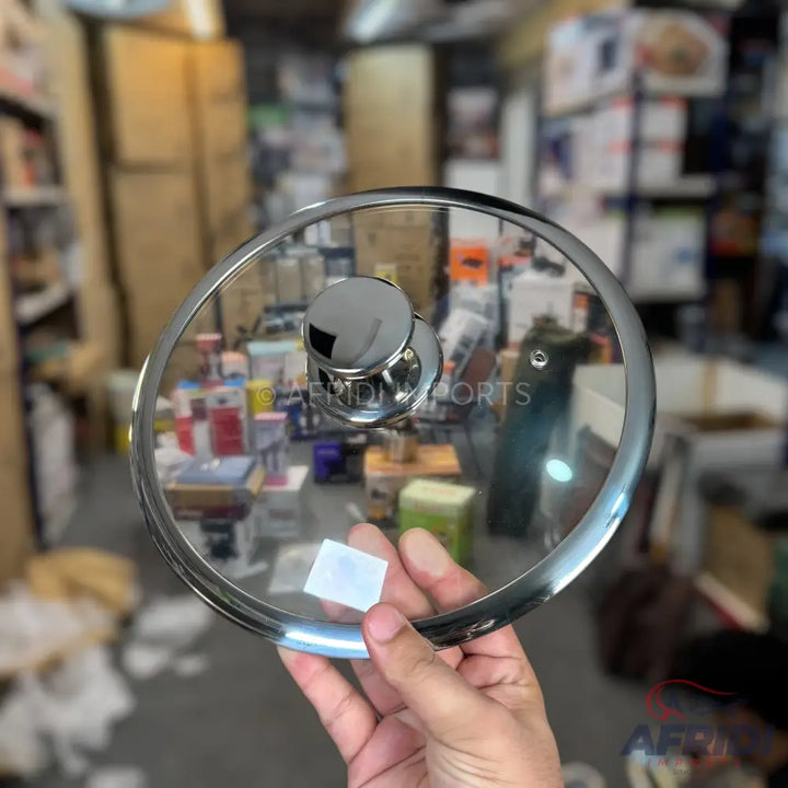A clear tempered glass pot lid with a polished metal rim and a chrome-finished knob handle.