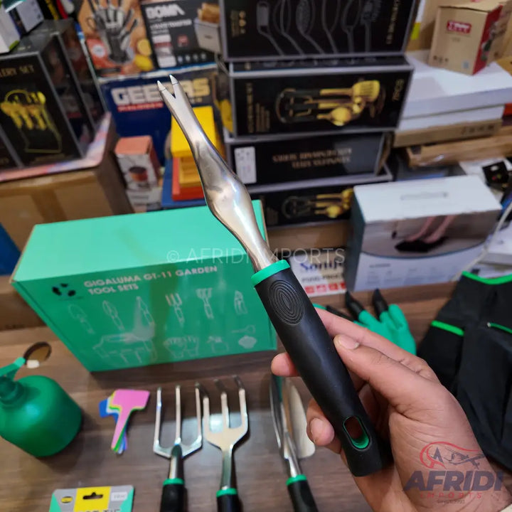 A hand-held weeding fork with a black handle and green accents.