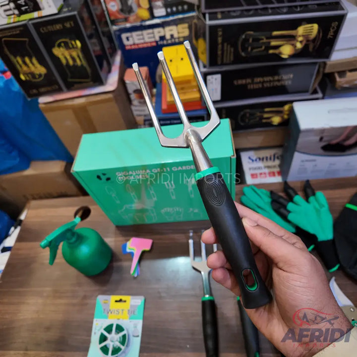 A hand garden hoe with a three-pronged fork on one end and a black and green ergonomic handle.