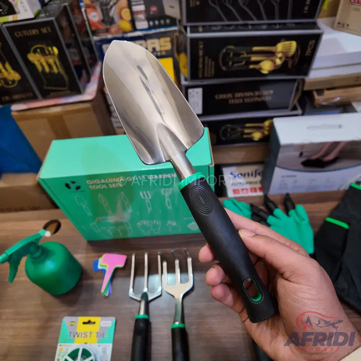 A stainless steel garden trowel with a black ergonomic handle and green accents.