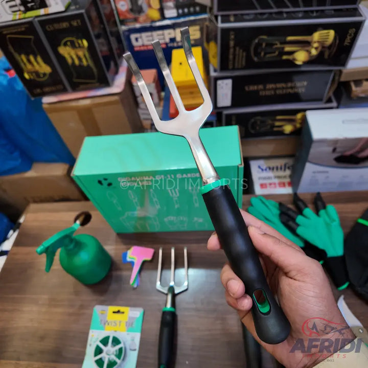 A stainless steel gardening fork with a black and green ergonomic handle.