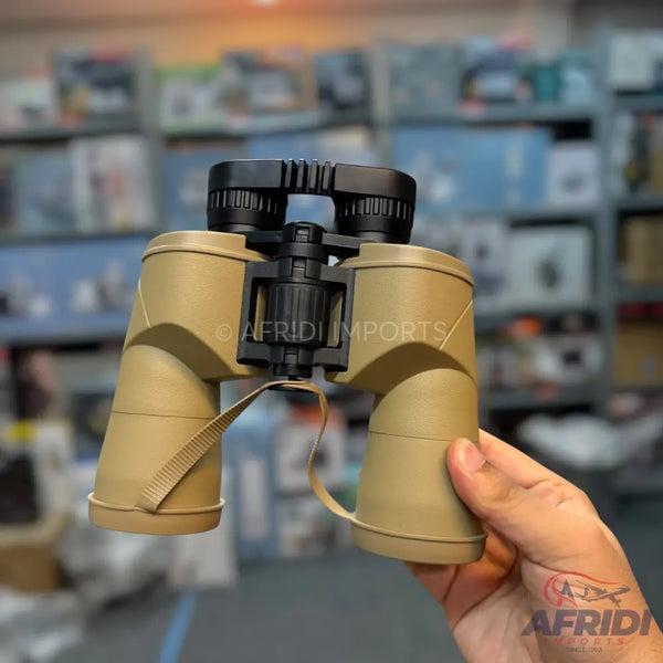 Tan-colored binoculars with black accents and a strap.