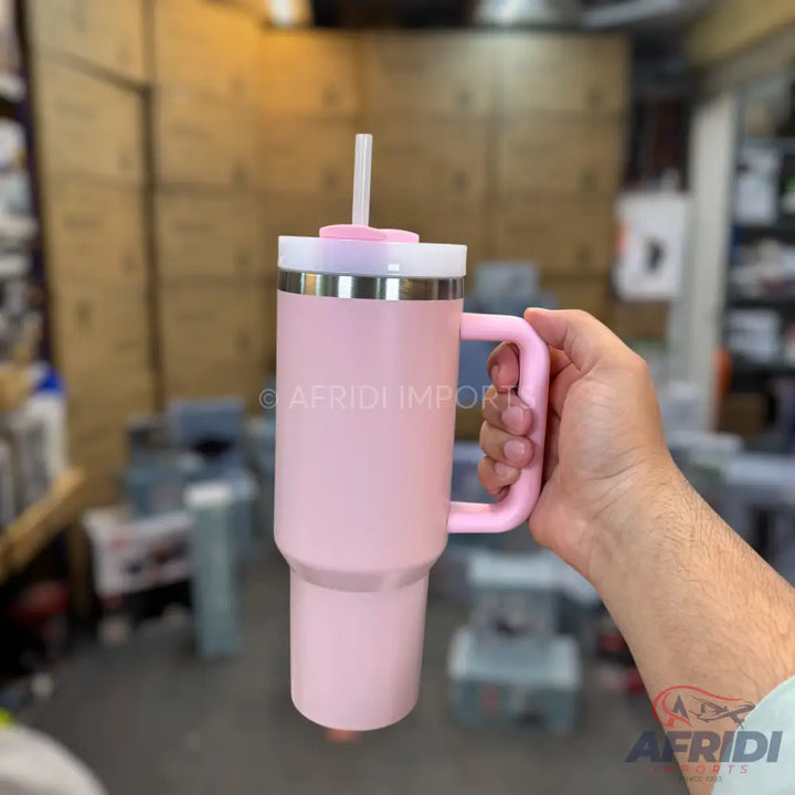 A pink insulated tumbler with a handle and a straw.