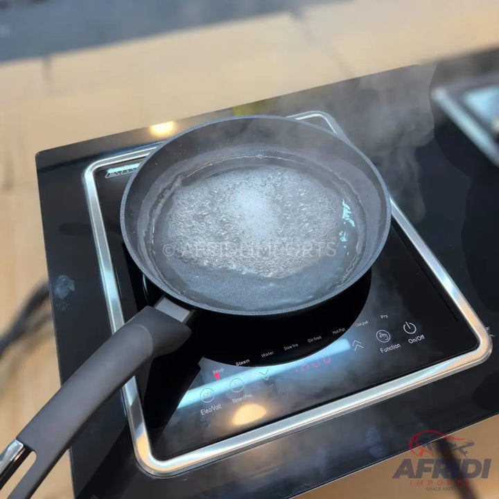 A pan of boiling water on a black electric induction cooktop.