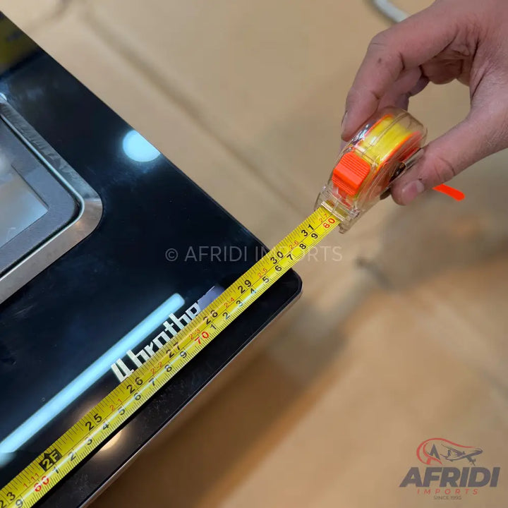 A person’s hand holding a tape measure, extending it across a black electronic scale.