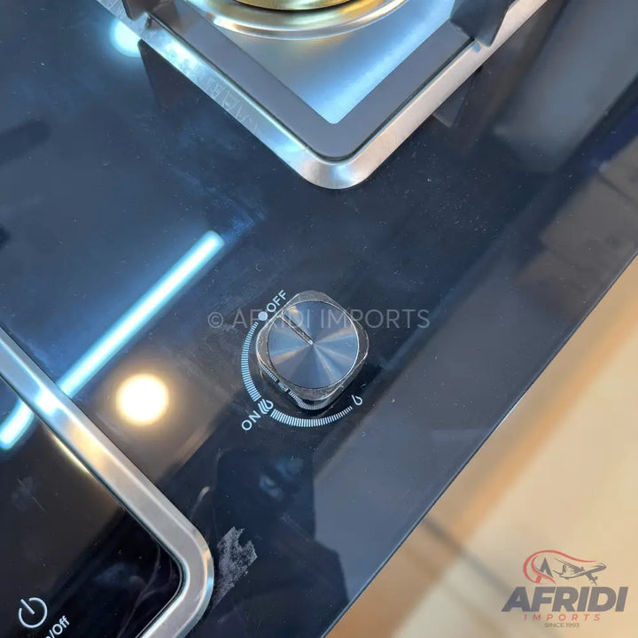 A modern black glass-top gas stove with a metal burner and control knob.