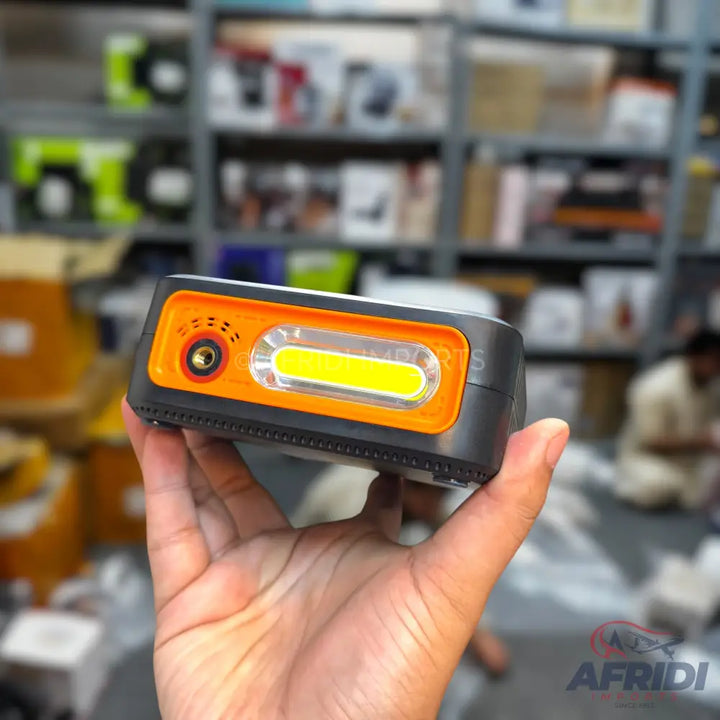 Handheld black and orange LED work light with a bright yellow COB strip and a red control knob.