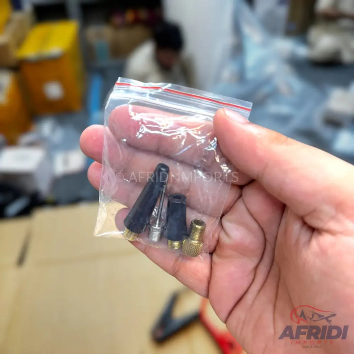 A small clear plastic bag containing three tire valve adapters.