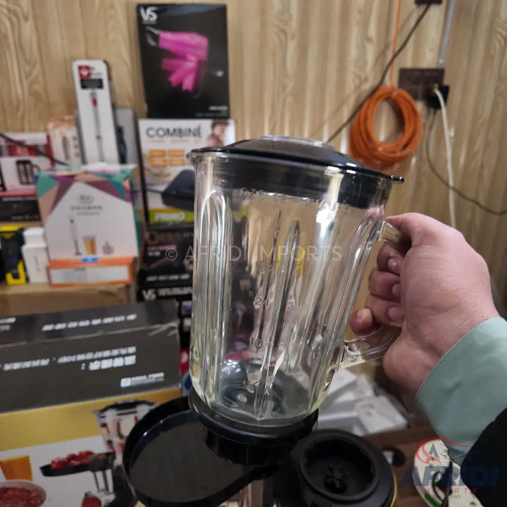 Glass blender jar with a black lid and handle.