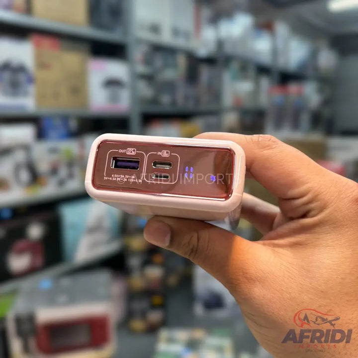 Hand holding a power bank with USB-A and USB-C ports.