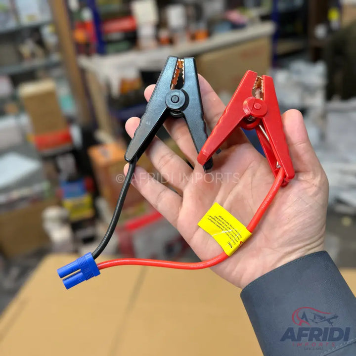 A pair of black and red battery jumper cable clamps with a blue connector.
