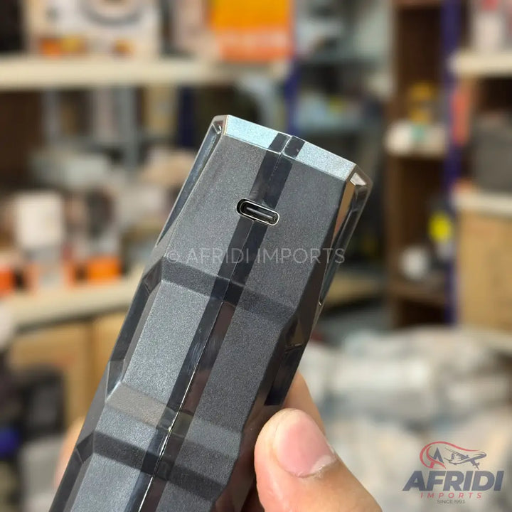 A sleek, dark gray portable electronic device with a USB-C charging port and a textured, geometric pattern.