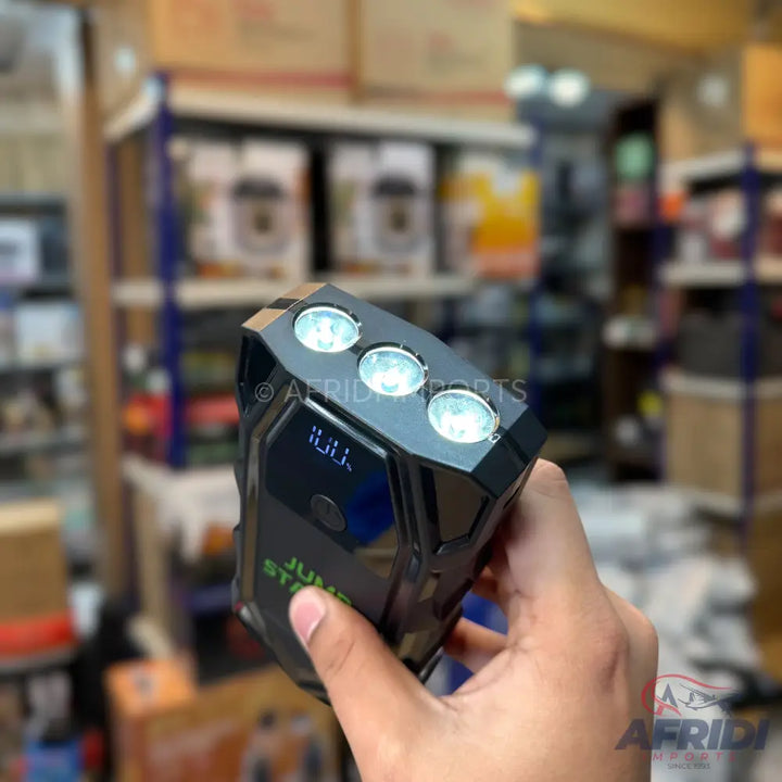 Black portable jump starter with three integrated LED lights and a digital display.