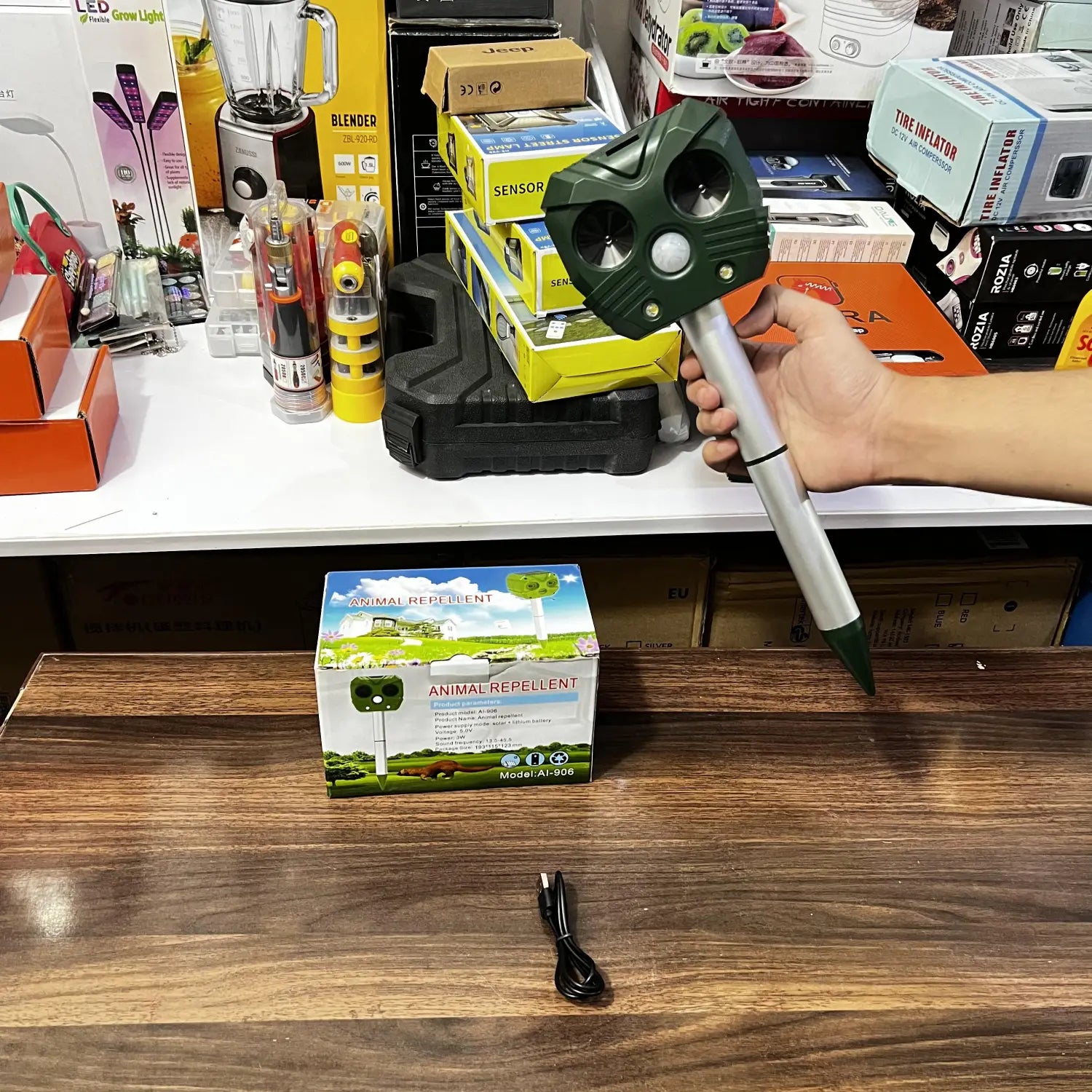 Handheld dark green and silver animal repellant device with pointed stake for pest control
