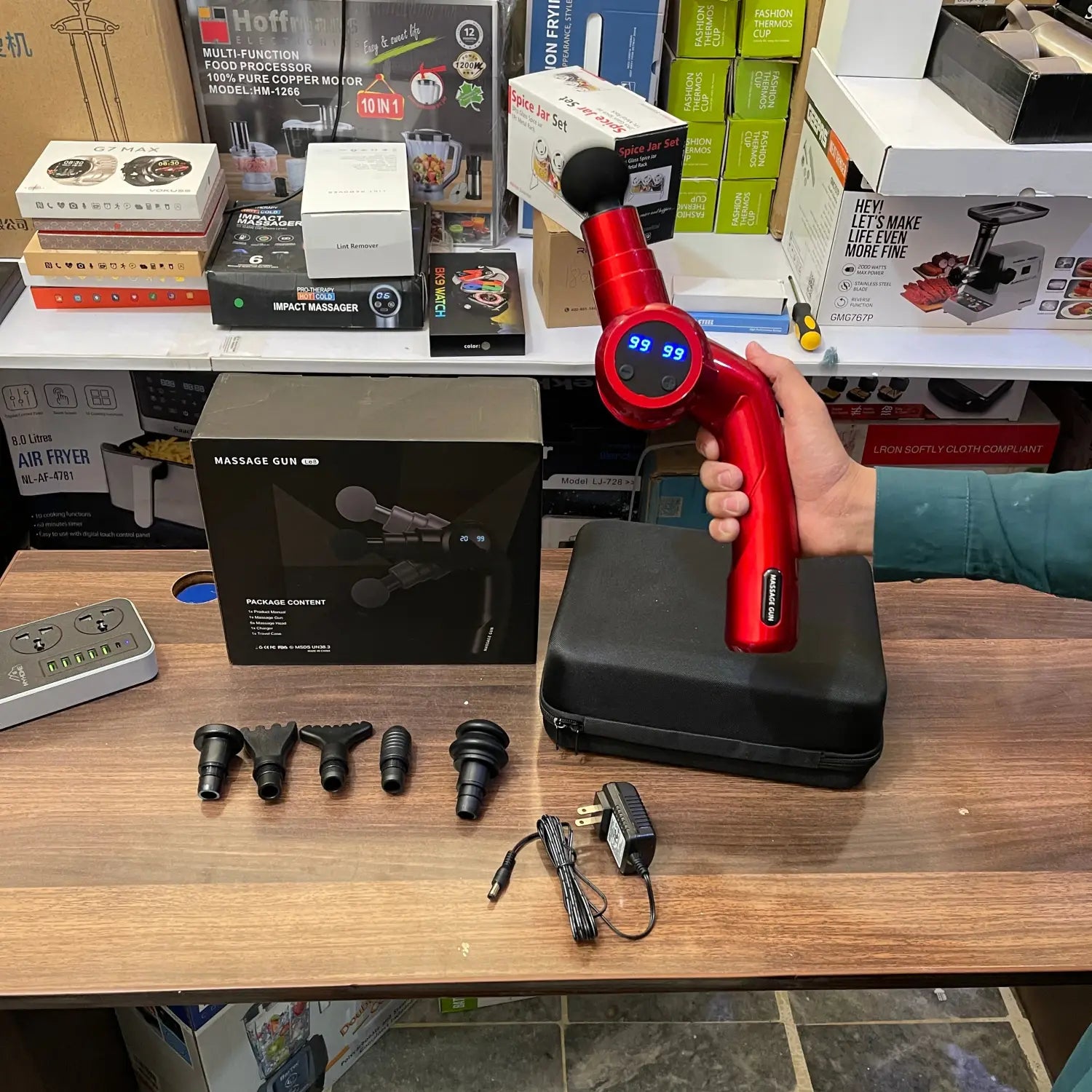 Red handheld folding massager gun LE8 with interchangeable heads, charger, and case