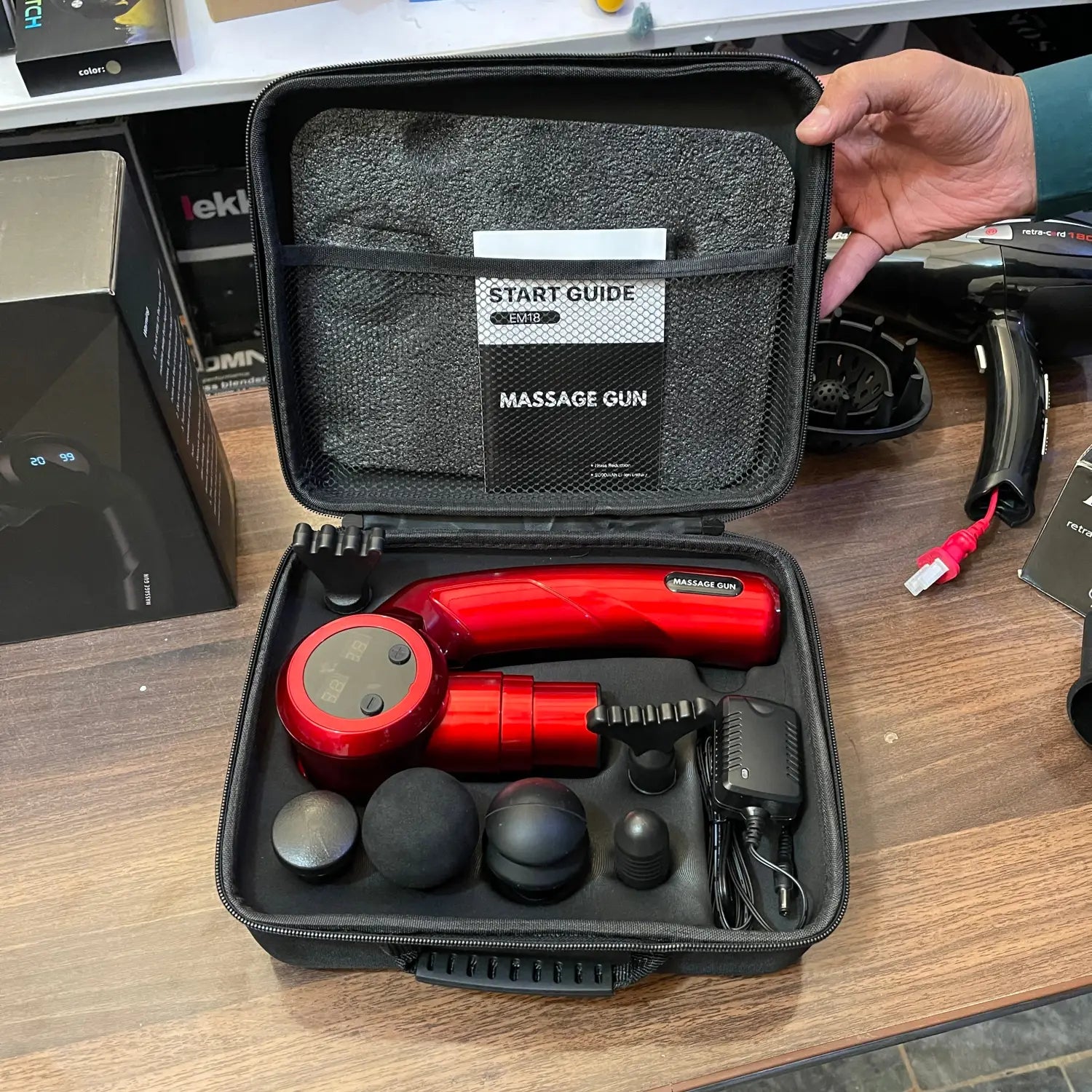 Red folding massager gun LE8 kit with interchangeable heads in a black zippered case.