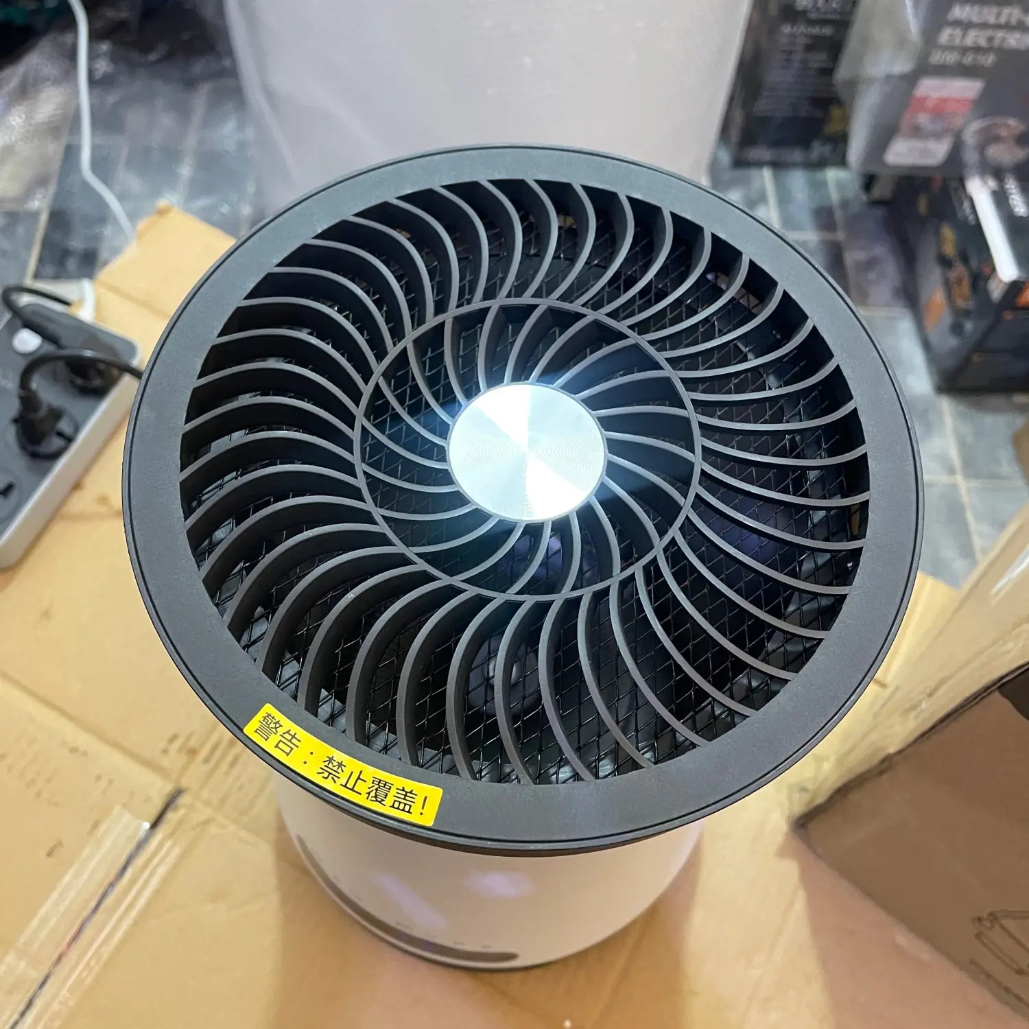 White and gray electric heater with spiral-patterned fan grill, mosquito killer design