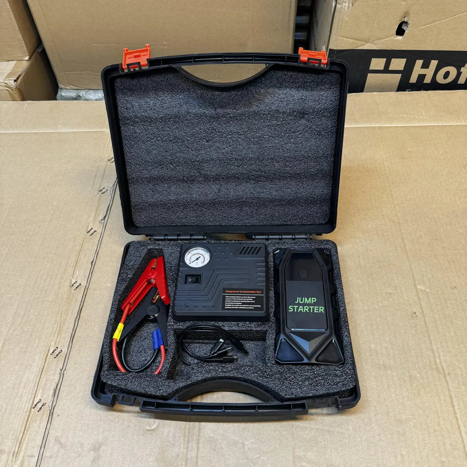 Portable car jump starter kit with tire inflator and battery clamps in protective case