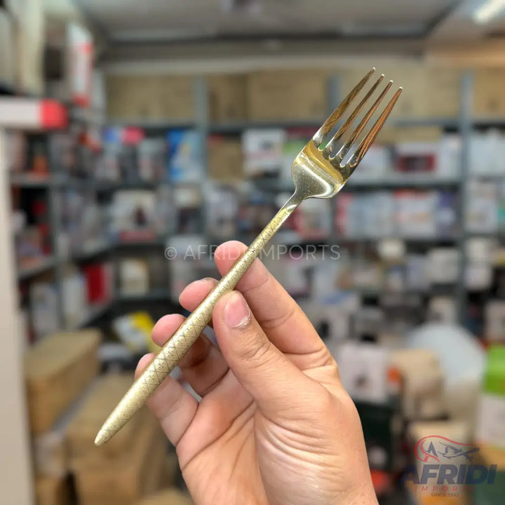 Gold-colored stainless steel dinner fork with a textured handle.