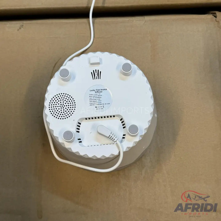 White circular aroma diffuser with a power cord connected.