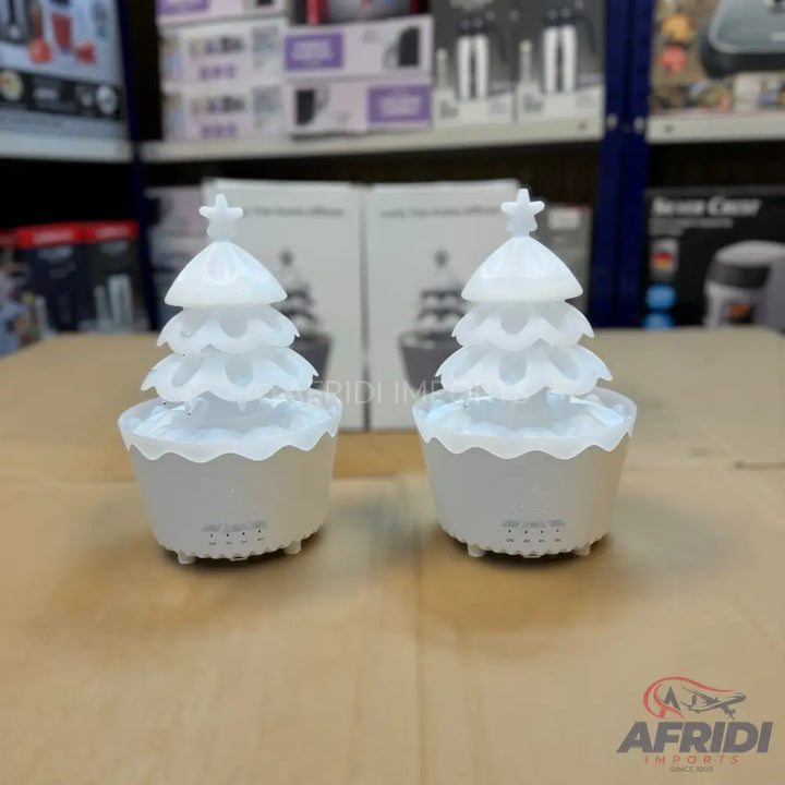 Two white, layered Christmas tree-shaped essential oil diffusers with star toppers.