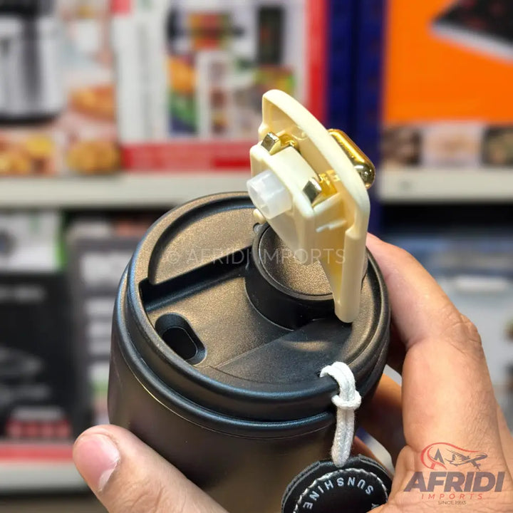 Black insulated tumbler with a cream-colored, openable lid, revealing internal components, and a ’SUNSHINE’ tag.