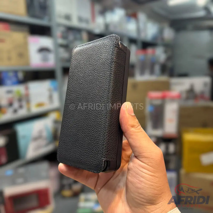 A person holding a closed black leather flip phone case.