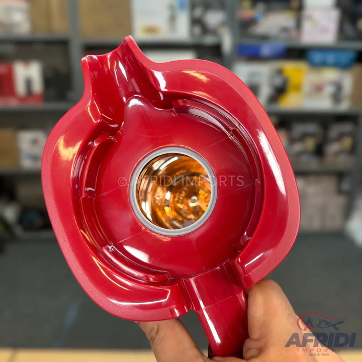 Red plastic car taillight housing with a reflective amber bulb socket.