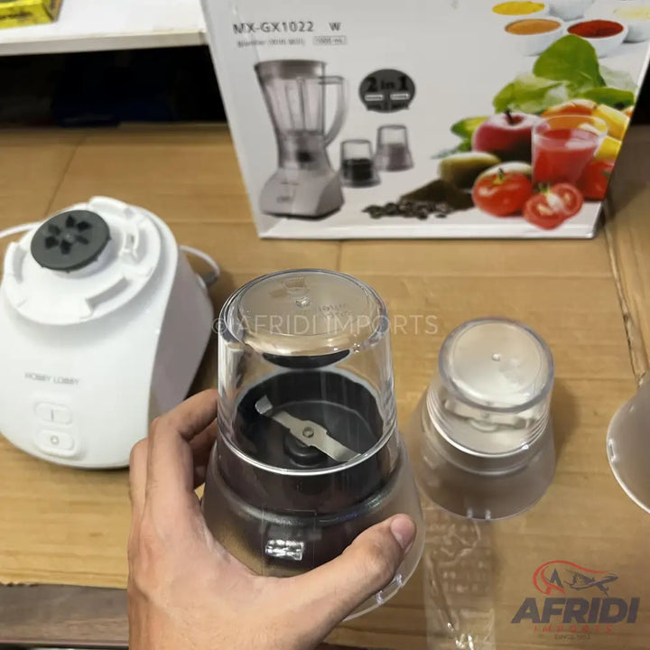 A white blender base with a detachable clear grinding attachment.