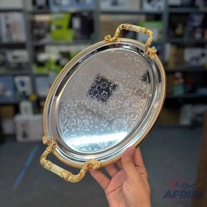 Oval silver serving tray with ornate gold handles and engraved floral patterns.