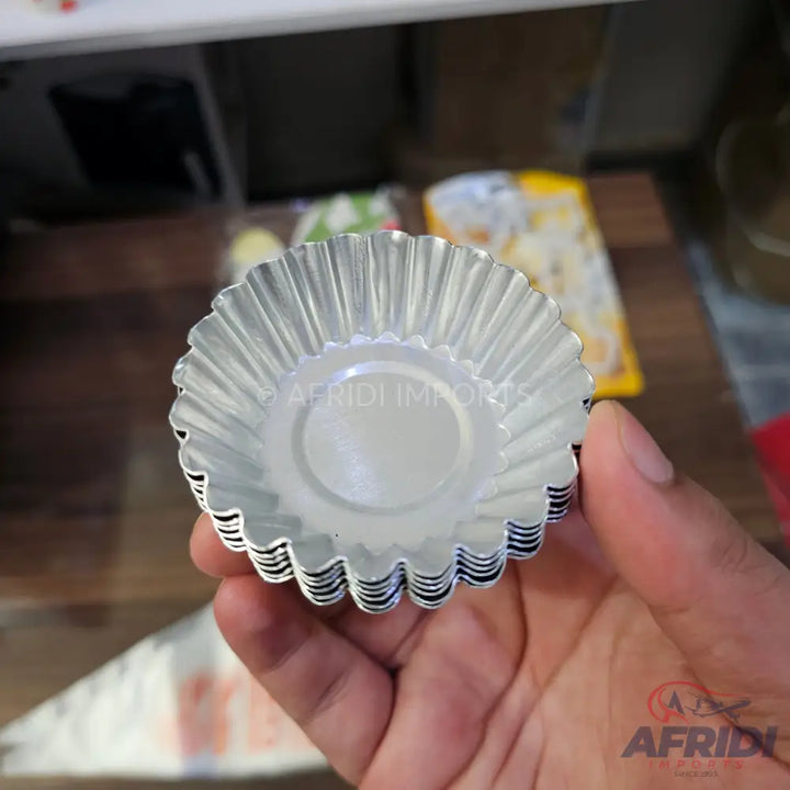 A stack of disposable fluted aluminum foil tart or cupcake liners.