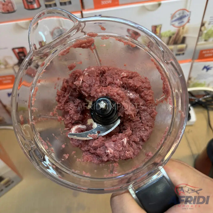 A clear food processor bowl filled with finely ground raw meat.