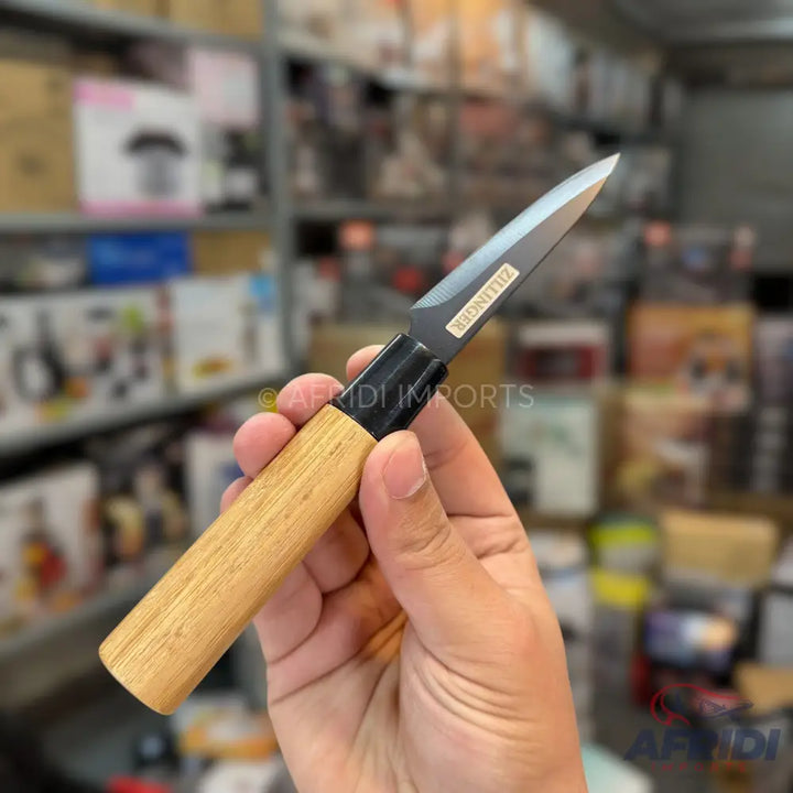 A hand holding a paring knife with a light wooden handle and a dark, pointed blade.