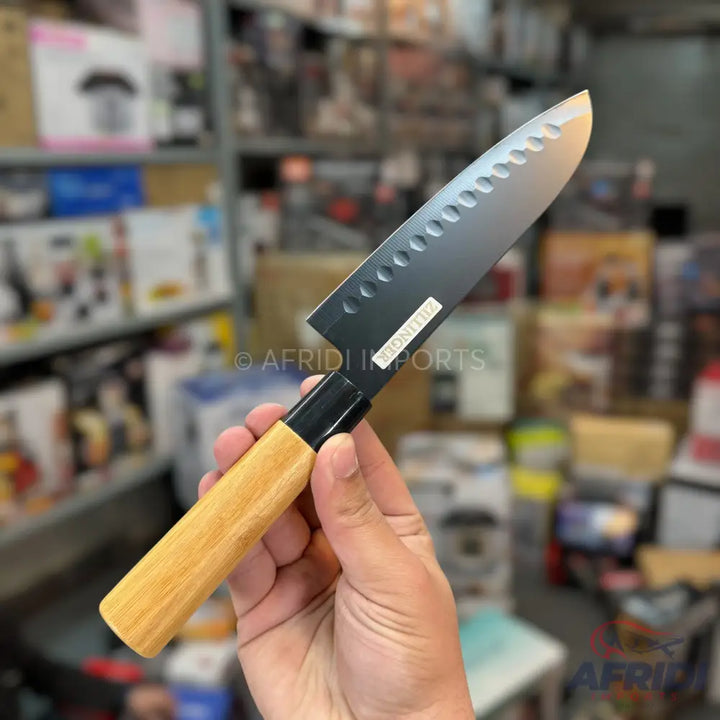 Black-bladed Santoku knife with a light wood handle.