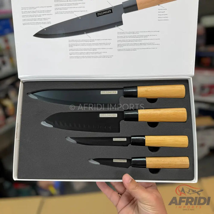 A set of four black-bladed kitchen knives with light wooden handles, presented in a fitted box.