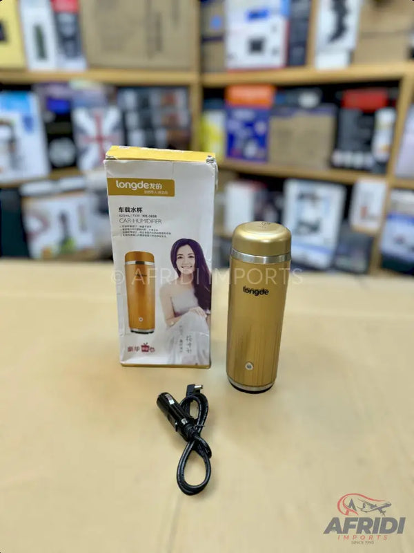 A golden, cylindrical, portable travel mug with an accompanying box and charging cable.